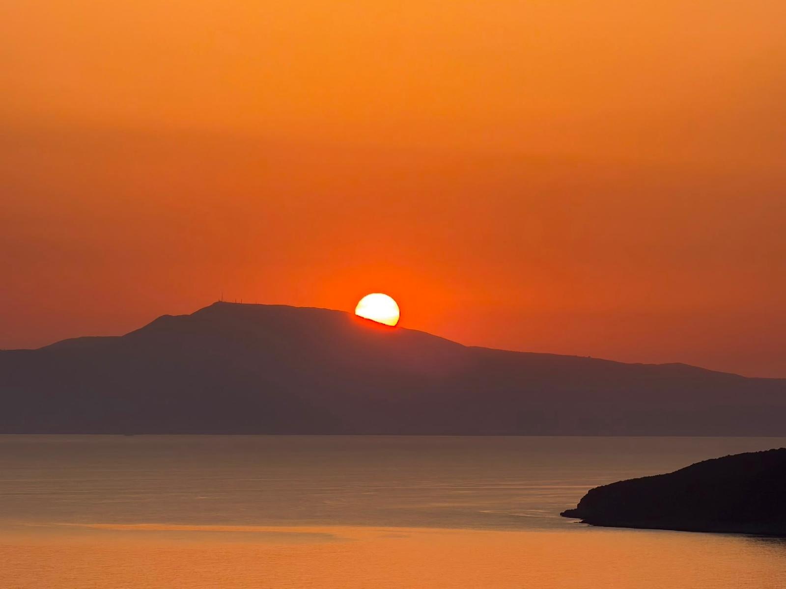 The sun setting behind the headland across the gulf.