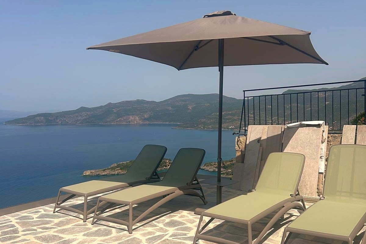 Loungers and a parasol on the terrace above the pool, the gulf beyond.